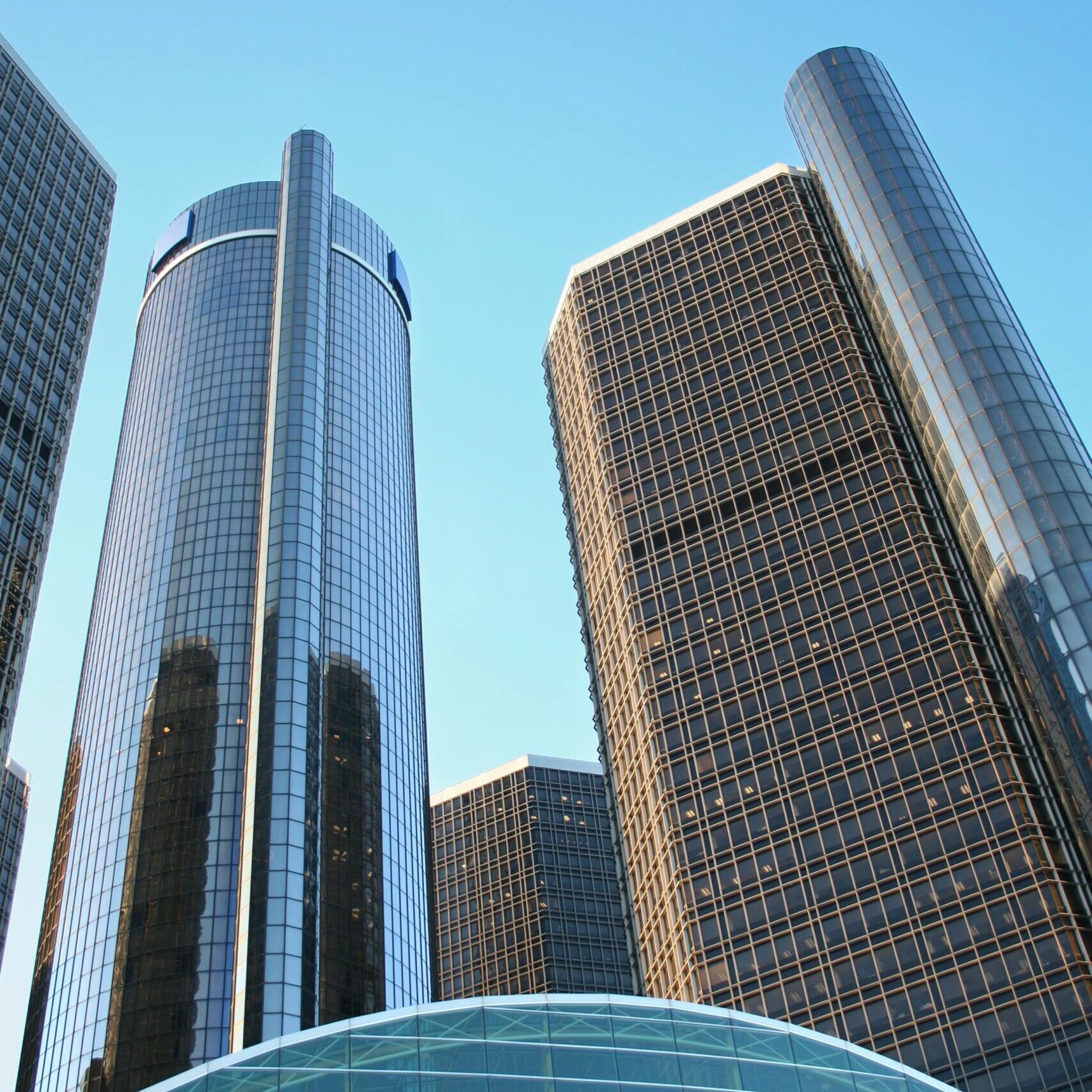 A striking view of Detroit's Renaissance Center skyscrapers with blue sky backdrop.